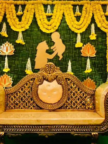 A classic Seemantham setup featuring a backdrop of woven banana leaves and marigold garlands. The mother and child silhouette cutout adds a personal and modern touch to the traditional decor.