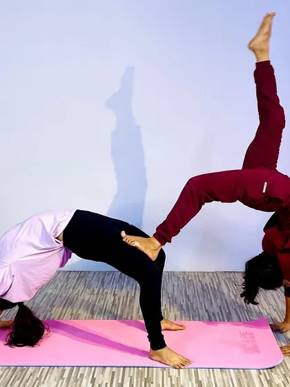 This advanced partner yoga pose combines a wheel pose with a one-legged variation, requiring immense trust, balance, and strength from both partners. It's a beautiful expression of connection.