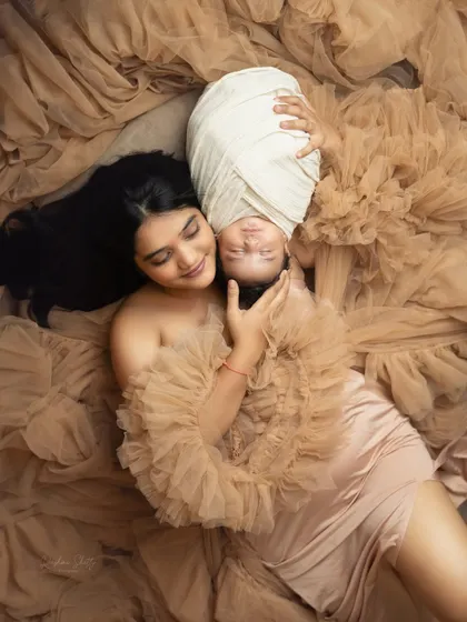An artistic overhead shot of a mother and her baby, enveloped in flowing fabric. This type of creative portrait is a beautiful way to celebrate the bond of motherhood.