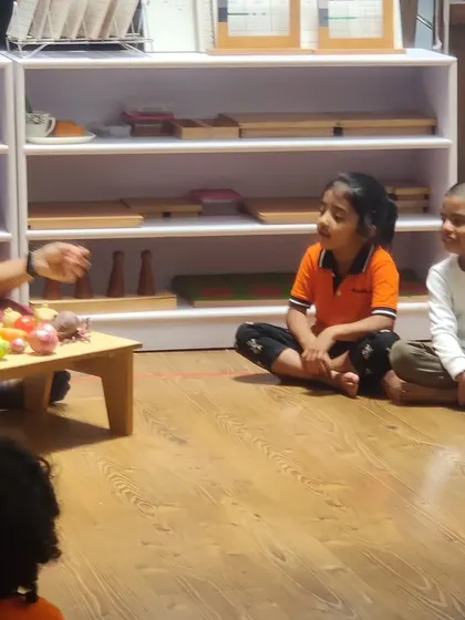 The children are captivated during a discussion about different vegetables. Using real examples allows them to see, touch, and smell, engaging multiple senses for a richer learning experience.