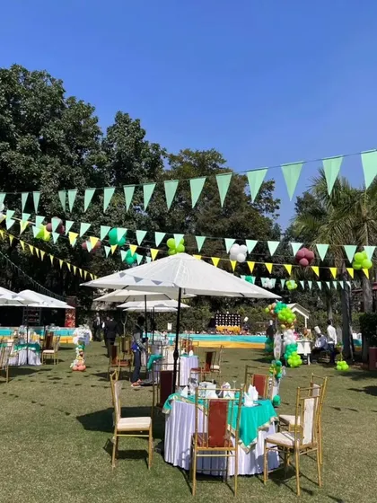 A view of the guest seating area at the outdoor jungle party, with green table covers and white umbrellas.