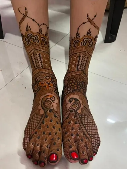 This foot design is rich with peacock motifs, with their feathers elegantly draping over the feet. The red nail polish provides a beautiful contrast.