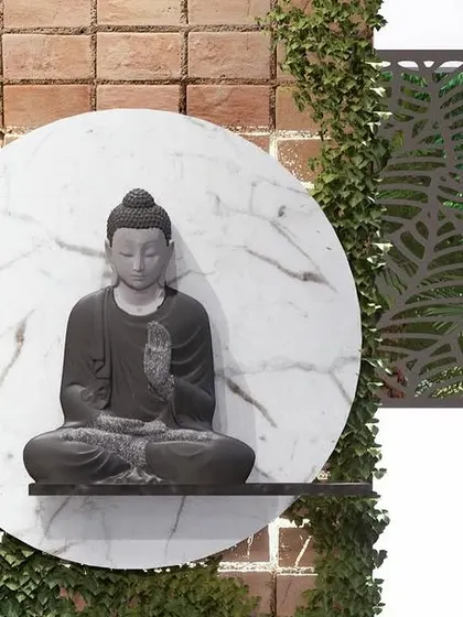 A close-up of the Buddha statue detail, mounted on a circular marble slab and flanked by a green wall and a decorative screen.