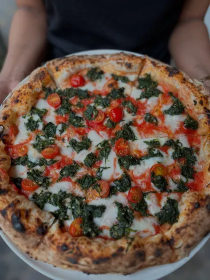 Holding up our Spinach and Garlic pizza. It's a perfect circle of veggie goodness.