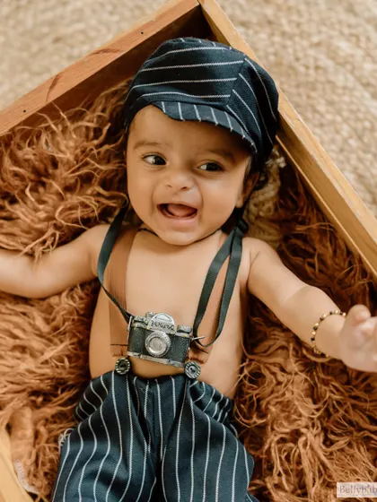 Ready to capture the world! This dapper little man with a vintage camera prop and pinstripe pants is the picture of retro charm.