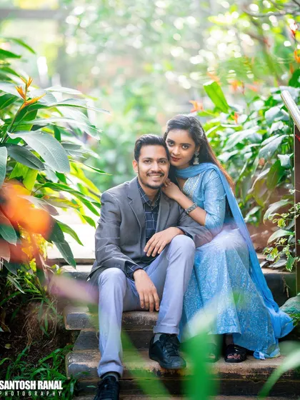 A classic, happy portrait of a couple sitting on steps surrounded by greenery.