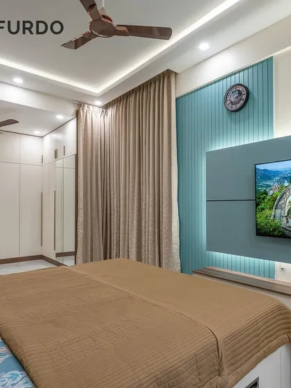 A well-designed bedroom featuring a sleek TV unit with backlit panels and a full-wall modular wardrobe. The neutral color scheme and warm lighting create a cozy and functional space.