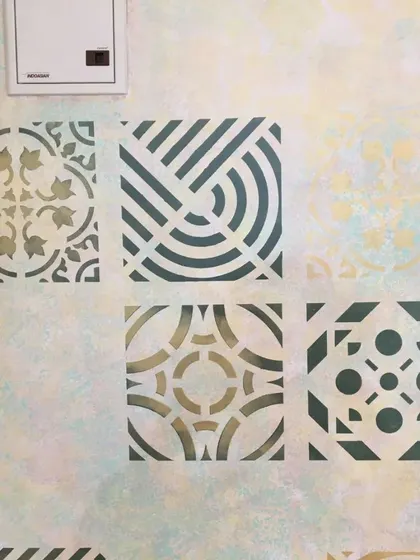 A detailed shot of the multi-patterned wall. Here you can see the different geometric and floral stencils we used, each with a clean and precise finish against the soft-focus background.