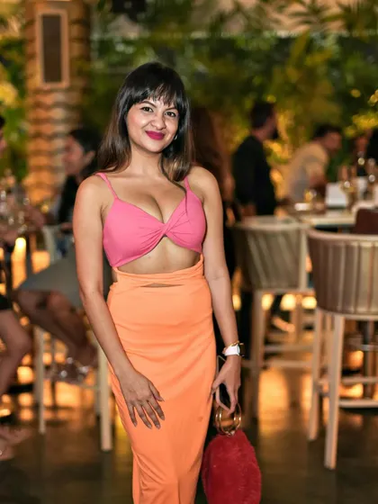A guest in a stunning orange and pink dress, adding a splash of color to the Pangeo rooftop.