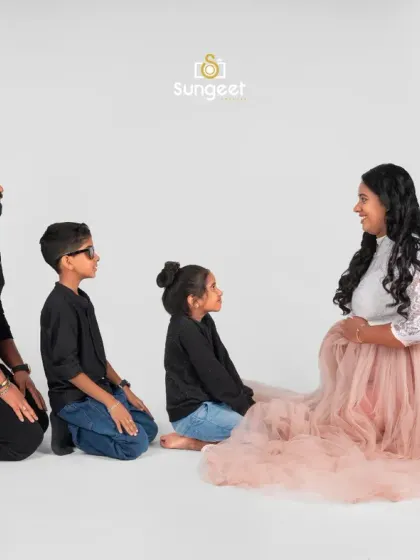 A modern family maternity portrait against a clean, white studio background. This shot beautifully includes the older children as they look lovingly at their mother, sharing in the excitement of the new arrival.