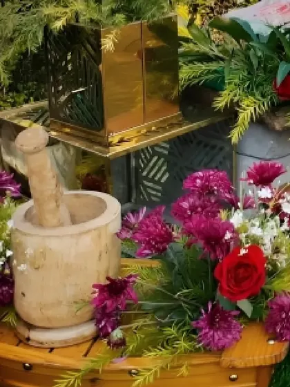 We use unique props like this wooden mortar and pestle to add a rustic and authentic charm to our buffet decor, complemented by vibrant purple and red flowers.