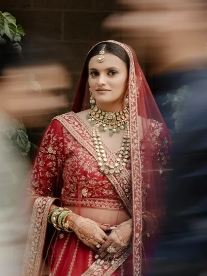 An ethereal shot with motion blur, focusing on the bride's calm and centered expression amidst the wedding hustle. Her makeup remains flawless.
