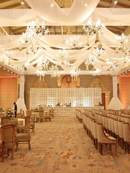 A grand ballroom setup with a ceiling of flowing white drapes and dozens of crystal chandeliers, creating a dreamy, ethereal atmosphere.