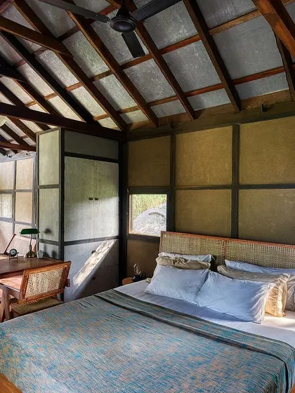 The bedroom and workspace area within the open-plan studio. The high, pitched roof with exposed beams enhances the sense of space, while the paneled walls add texture and rhythm to the interior.