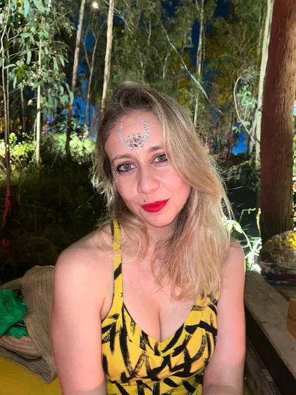 A glamorous festival look with a bold red lip and a sparkling rhinestone design on the forehead.