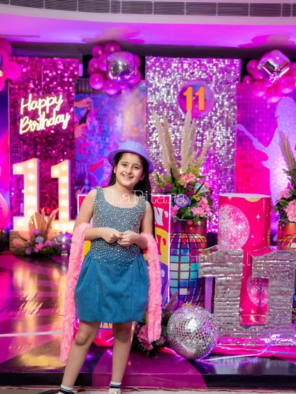 The birthday girl posing in her disco-themed outfit, perfectly complementing the vibrant and sparkly decor.