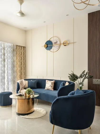 This angle highlights the cohesion in the living space, from the custom curved sofa and accent chairs to the metallic and glass center table, all unified by a palette of deep blue, gold, and neutral tones.