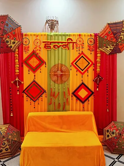 A simple and elegant Haldi backdrop with a comfortable seating arrangement, perfect for intimate home functions.