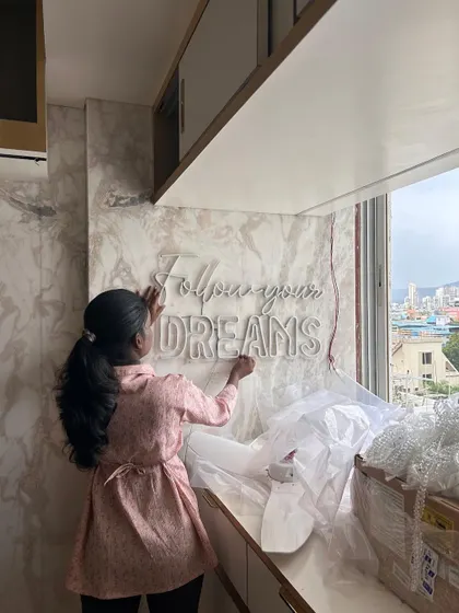 I am a hands-on architect, personally overseeing the installation of key design elements. Here I am on-site at a Vashi project, placing a "Follow your Dreams" neon sign, adding a final touch of inspiration to the space.