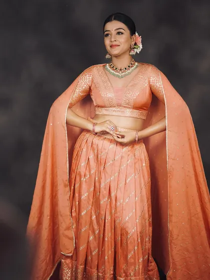 The elegant silhouette of the peach lehenga with its unique cape sleeves, perfect for a memorable entrance.