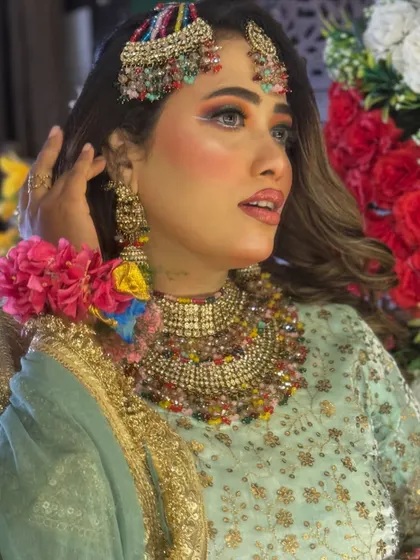 This look features colorful jewelry and fresh flower bracelets, perfect for a Haldi or Mehendi ceremony. The makeup is bright and fresh, with a pop of color on the eyes.