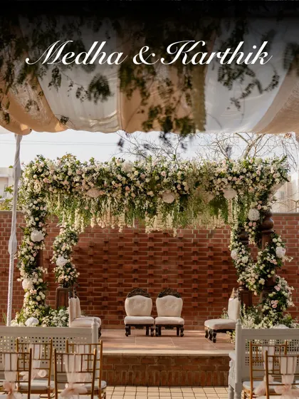Against a rustic brick wall, this engagement mandap is a vision of modern elegance. A lush canopy of hanging white and pink florals creates a dreamy, fairytale-like setting, perfect for a contemporary celebration at The Secret Grove.