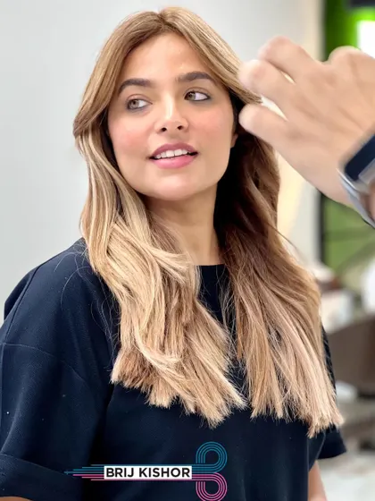 A close-up of the face-framing pieces in this creamy peach ash blonde look. The color beautifully complements her skin tone.