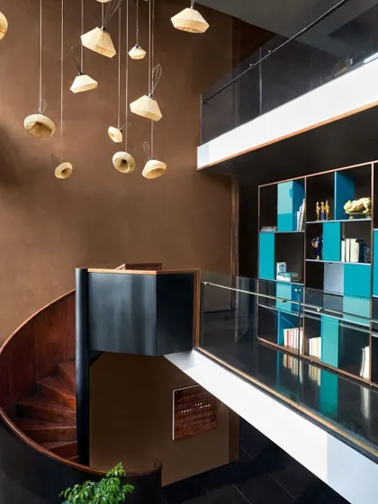 This spiral staircase, crafted in matte black metal and polished wood, is more than a connector; it's a sculptural punctuation mark in the architecture. Its form anchors the double-height space while allowing light to move freely.