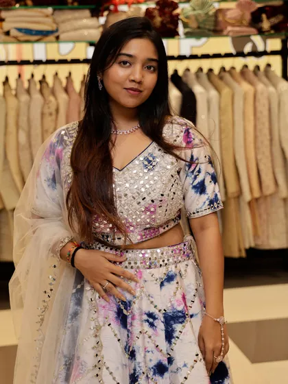 A close-up of the white tie-dye lehenga, showing the vibrant colors and sparkling mirror work.
