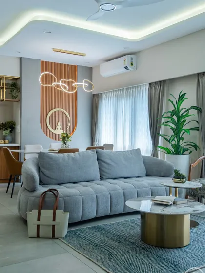 A view from the plush grey sofa towards the dining area. The open layout is unified by a consistent color palette and lighting design, including a modern looped chandelier over the dining table.