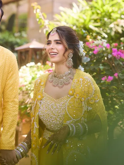A beautiful candid of the couple. Her joyful expression is the best testament to a successful Haldi look that feels comfortable and beautiful.