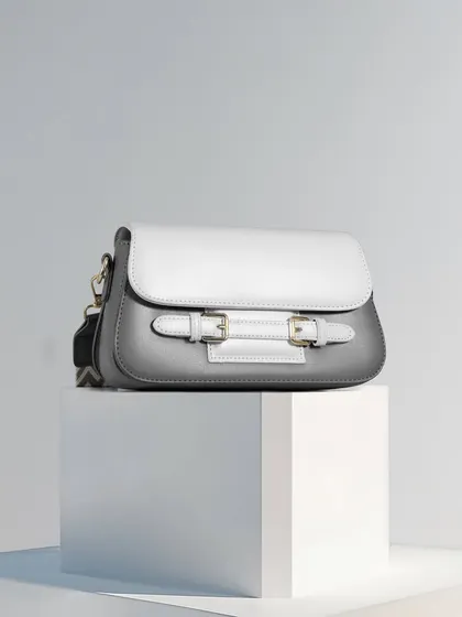 A minimalist composition featuring a grey and white handbag on a white block. The clean lines, simple color scheme, and balanced composition create a feeling of modern elegance and simplicity.