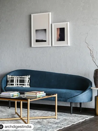 A feature from Architectural Digest showcasing the lounge area of the AMC Chairman's office. The elegant blue sofa, brass coffee table, and minimalist art create a space that is both stylish and comfortable.