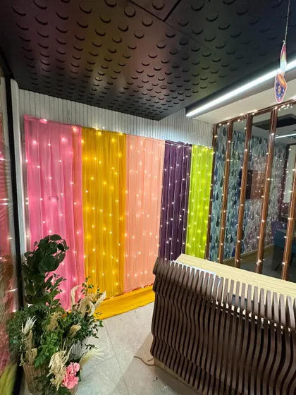 A colorful photo backdrop created with drapes and fairy lights for an office Diwali party.