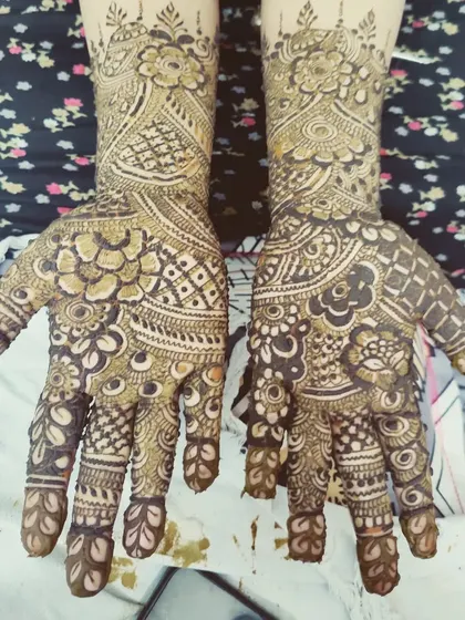 The palms are filled with a rich tapestry of traditional Indian mehndi patterns, perfect for a bride.