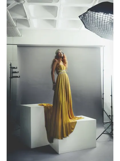 The color version of the behind-the-scenes studio shot. This shows the final lighting effect on the model and the flowing yellow gown, giving a clearer picture of the on-set environment.