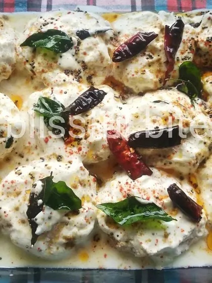 A tray of my delicious Dahi Vade, a popular South Asian snack. The soft vadas are drenched in thick, seasoned yogurt and garnished with spices, curry leaves, and red chilies.