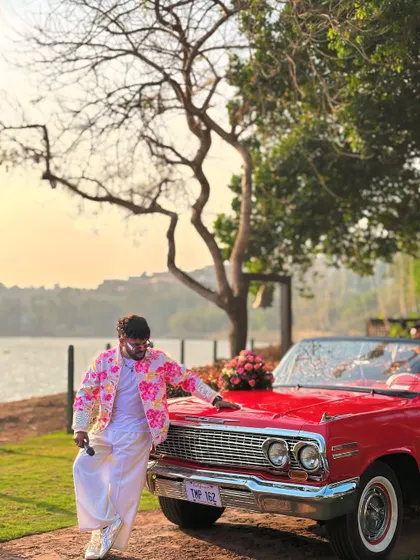 Posing with a vintage car before leading the baraat. Every detail, from the decor to the transport, adds to the grandeur of the wedding.