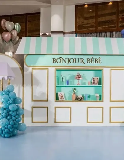 Bonjour Bébé! We transported guests to a Parisian street with this charming baby shower setup. Featuring a custom patisserie facade, a Ladurée-inspired cart, and vibrant balloon garlands, this theme is perfect for a chic and stylish celebration.