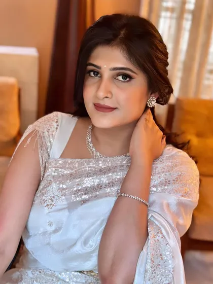 A beautiful portrait showcasing the complete look. The half-up hairstyle and minimalist jewelry let the sparkling saree and flawless makeup shine.