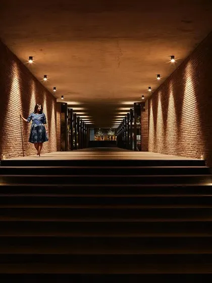 A dramatic, brick-lined corridor at Samavana, where carefully placed uplighting creates a powerful sense of arrival. This long, symmetrical passage is designed to build anticipation as guests move through the space.