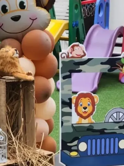 A close-up of the jungle party decor, showing the monkey balloon, a lion plushie, and the fun jeep-themed photo frame for kids to peek through.