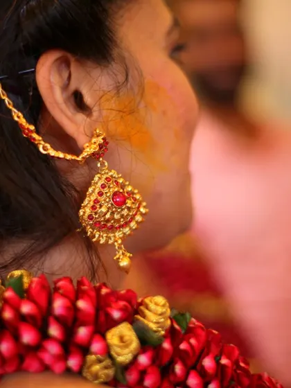 A detail shot focusing on a bride's traditional gold earring and the floral garland in her hair.
