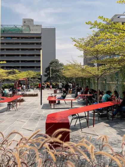 This wider view of the Red Ribbon Plaza shows how the installation meanders through the space, connecting different areas and providing ample seating. It transforms a simple plaza into a vibrant hub for social interaction.