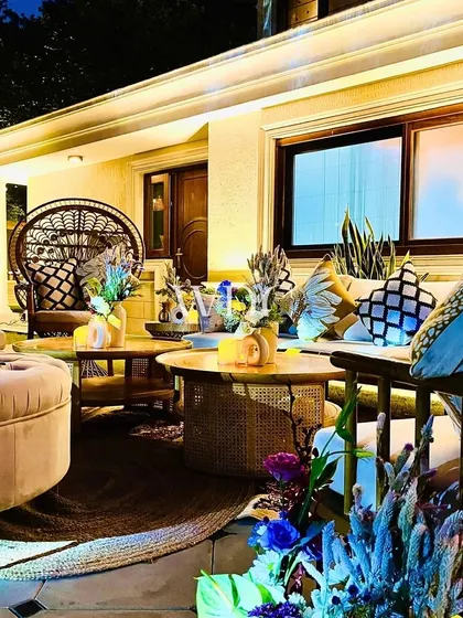A cozy and stylish lounge area with a mix of modern and bohemian furniture, including a beautiful peacock swing chair.
