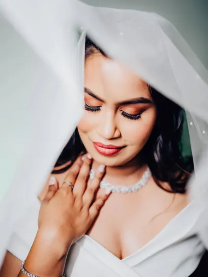 An artistic shot through the veil. The soft, diffused light creates a dreamy and romantic mood, highlighting her beautiful makeup.