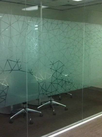 A geometric line pattern on a frosted film gives this glass-walled conference room a dynamic and modern feel. It ensures conversations stay private while contributing to the office's contemporary aesthetic.