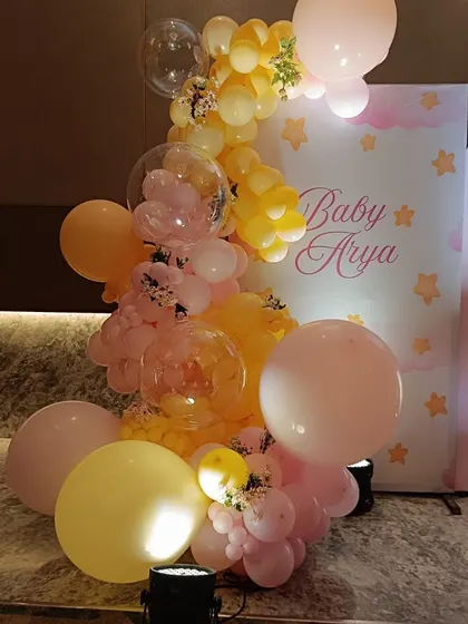 A beautiful balloon arrangement in shades of pink and yellow, accenting a personalized "Baby Arya" backdrop for a bunny-themed celebration.