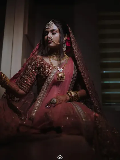 A moody and cinematic portrait of a bride in a deep red lehenga, using shadows and light to create a dramatic effect.