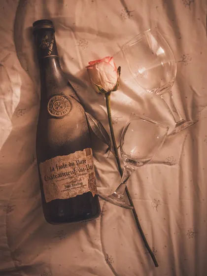 A flatlay of the vintage wine bottle and glasses on a soft, textured fabric, creating a romantic and nostalgic mood for Valentine's Day.